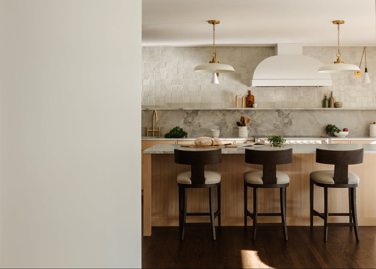 Modern kitchen with bar stools and a light-colored backsplash.